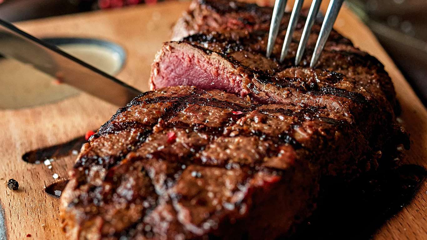 grilled meat with tomato and green vegetable on black pan